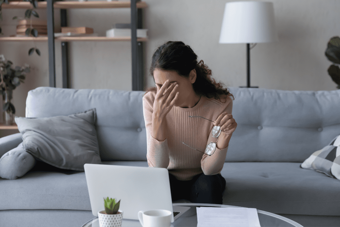 Woman sitting in front of laptop rubbing her eyes