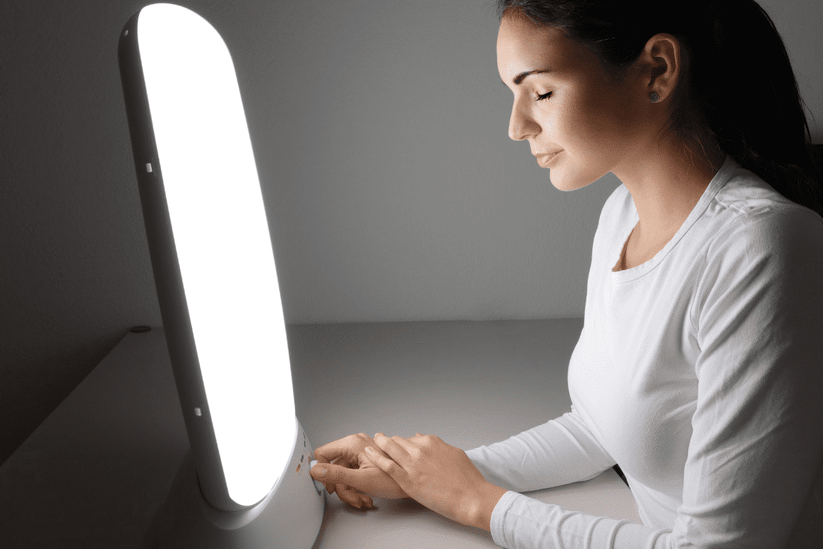 Woman sitting in front of a light therapy box. Lighting is important to our mental health.