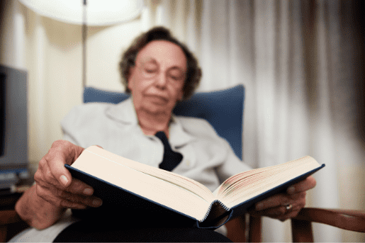 Senior adult reading a book. Library programming such as outreach programs have made books available to those stuck at home during the pandemic.