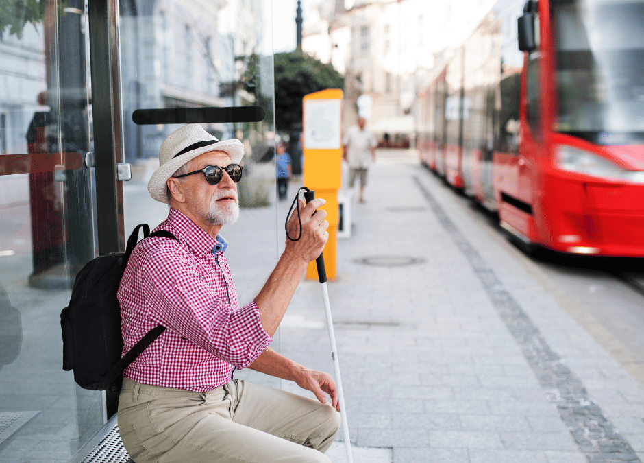 Man with white cane waiting at bus stop