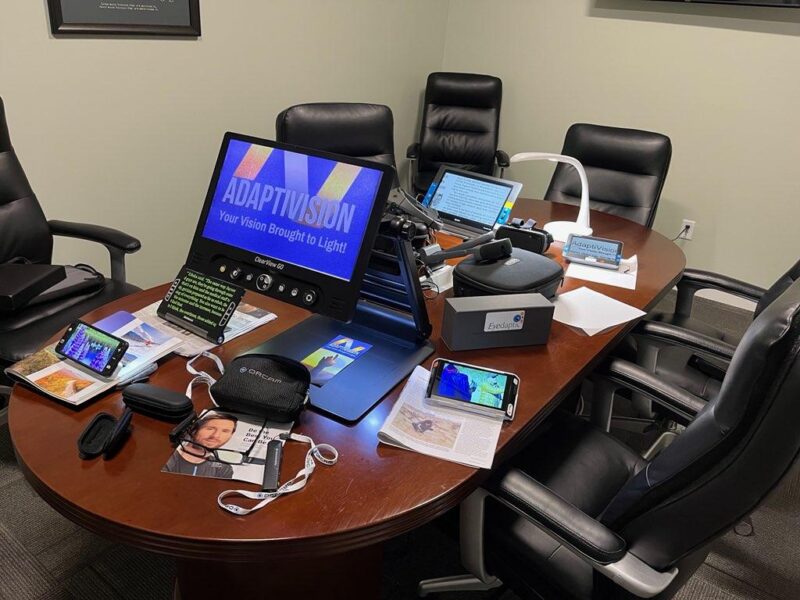 Conference table and chairs showing an array of assistive technology for low vision and blindness