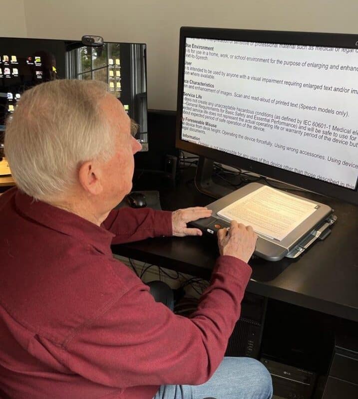 Clark Montgomery using the moveable tray on the Optelec ClearView C Speech destop video magnifier