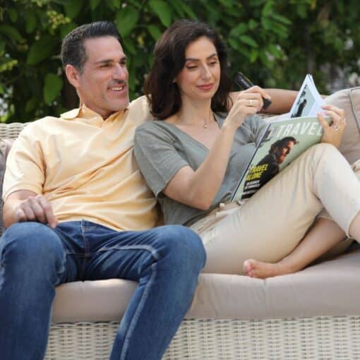 Two people sitting on a couch. One is reading a magazine with the OrCam Read 3.