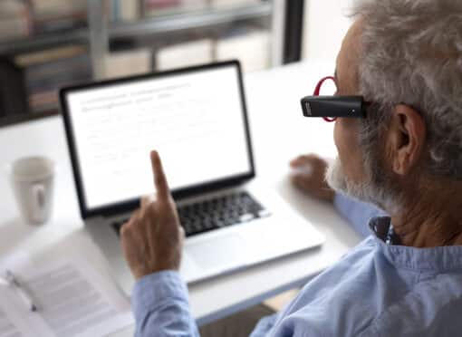 Person reading a computer screen with the OrCam MyEye 3 Pro