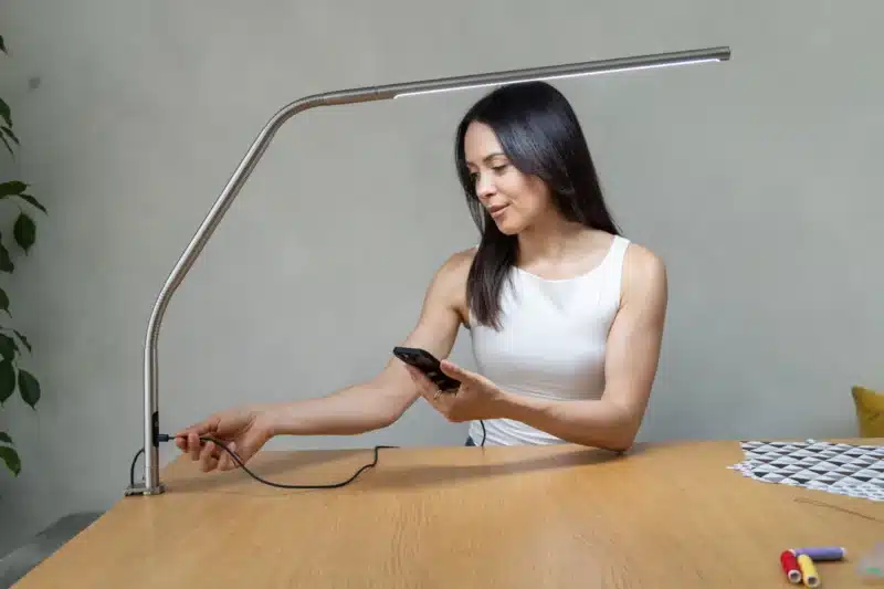 Daylight Slimline 4 Table Lamp with person plugging in a mobile phone
