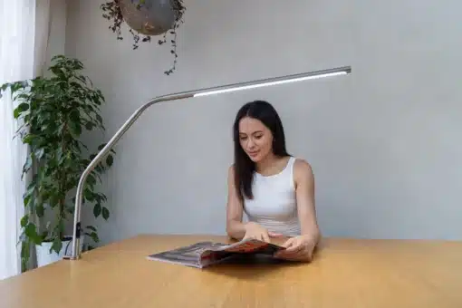 Daylight Slimline 4 Table Lamp with person reading a magazine