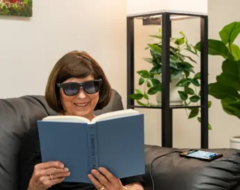 Person wearing EYE7 smart glasses for low vision while reading